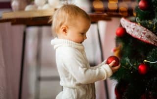 Child admiring Christmas ornament on tree