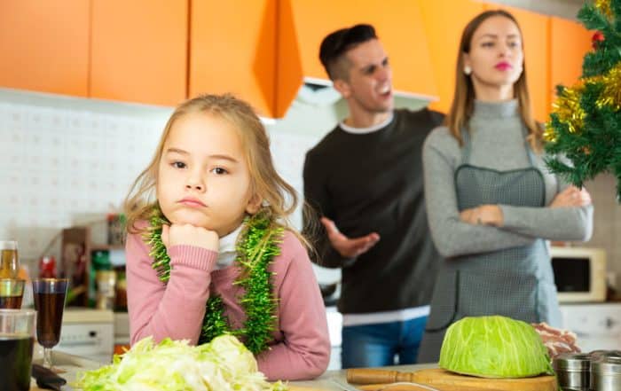 Unhappy child frustrated by adult parents stress over the holidays.