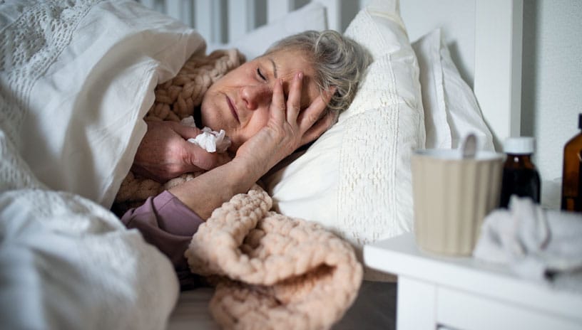 Woman with influenza laying in bed sick